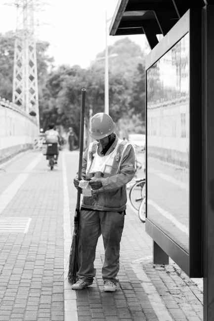 services-01 A man cleaning a glass barrier outdoors with a squeegee, surrounded by greenery.