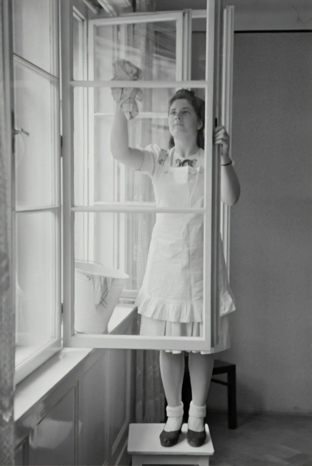 A man cleaning a glass window with a mop in grayscale, showcasing professional work.