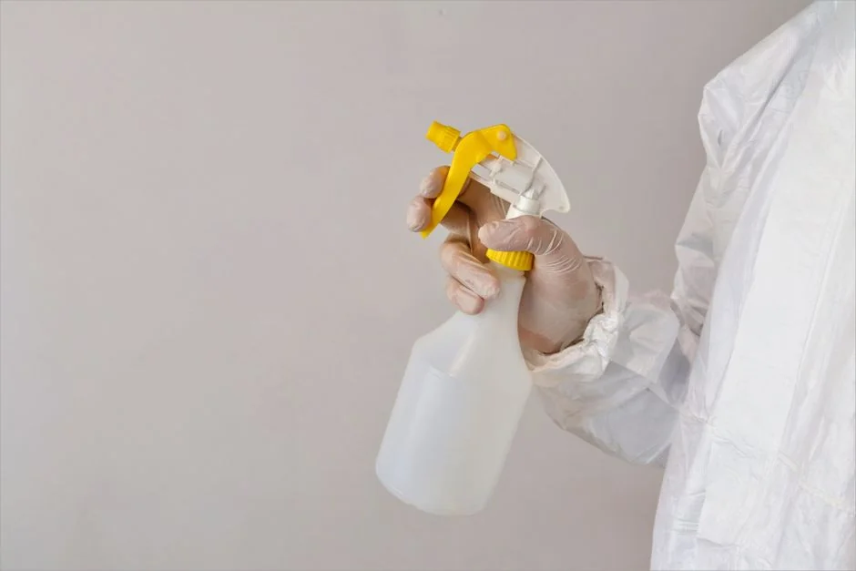 A man wiping down a glass door inside with a spray bottle and cloth.